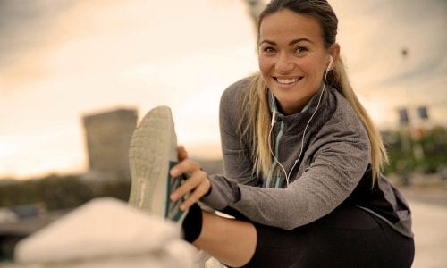 Young, single, athletic woman stretching before a run: health insurance comparison