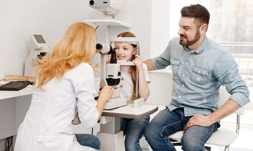 Father watches daughter have an eye exam test